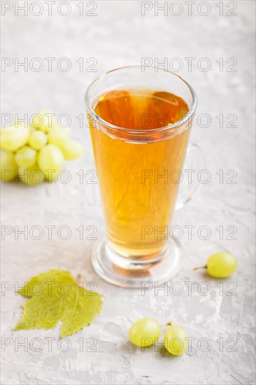Glass of green grape juice on a gray concrete background. Morninig, spring, healthy drink concept. Side view, close up