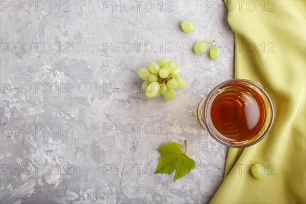 Glass of green grape juice with green textile on a gray concrete background. Morninig, spring, healthy drink concept. Top view, copy space, flat lay