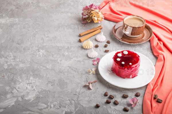 Red cake with souffle cream with cup of coffee on a gray concrete background and red textile. side view, copy space