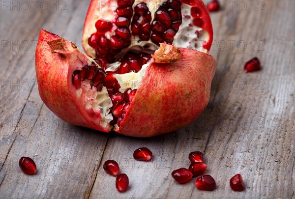 Opened ripe garnet with seeds on a rustic wooden background