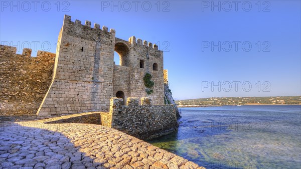 Part of a castle on rocks by the sea under a deep blue sky, sea fortress Methoni, Peloponnese, Greece, Europe