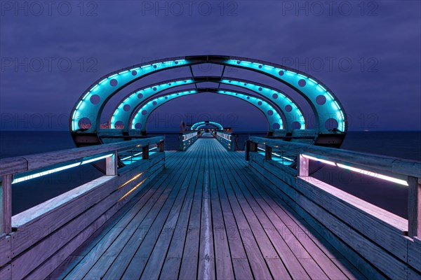 Long exposure during the blue hour of the pier of Kellenhusen at the Baltic Sea with blue illuminated arcades