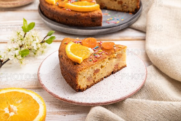 Orange cake and a cup of coffee on a white wooden background and linen textile. Side view, close up