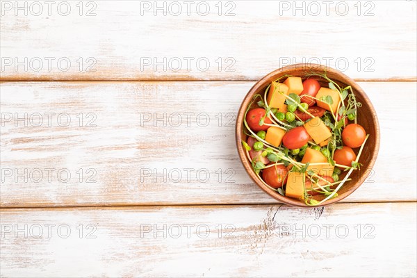 Vegetarian vegetable salad of tomatoes, pumpkin, microgreen pea sprouts on white wooden background. Top view, flat lay, copy space