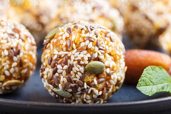 Energy ball cakes with dried apricots, sesame, linen, walnuts and dates with green mint leaves on a blue ceramic plate. side view, close up, macro. vegan homemade candy