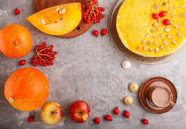 Traditional american sweet pumpkin pie decorated with hawthorn red berries and pumpkin seeds with cup of coffee on a gray concrete background. top view, flat lay, copy space