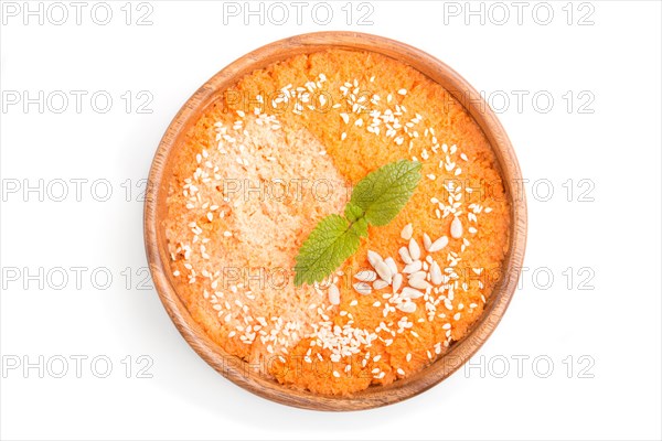 Carrot cream soup with sesame seeds in wooden bowl isolated on white background. top view, flat lay, close up