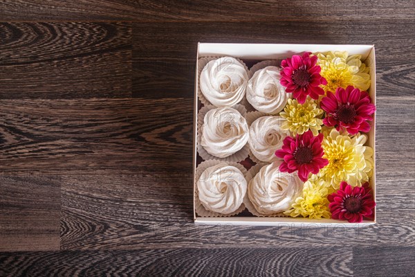 White box with white homemade zephyr and sunflowers and chrysanthemums on gray wooden background. copy space