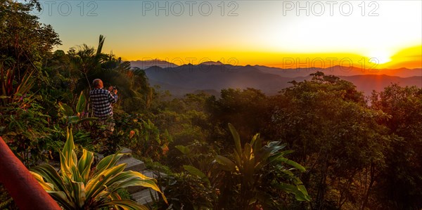 A tourist photographs the sunrise at Finca Don Gabriel, Pluma Hidalgo, Pochutla, Oxaca state, Sierra Madre del Sur, Mexico, Central America