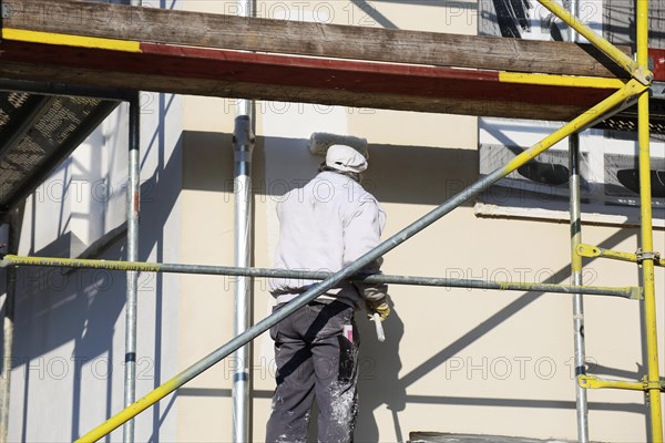 Painter painting the facade of a new residential building (Mutterstadt development area, Rhineland-Palatinate)