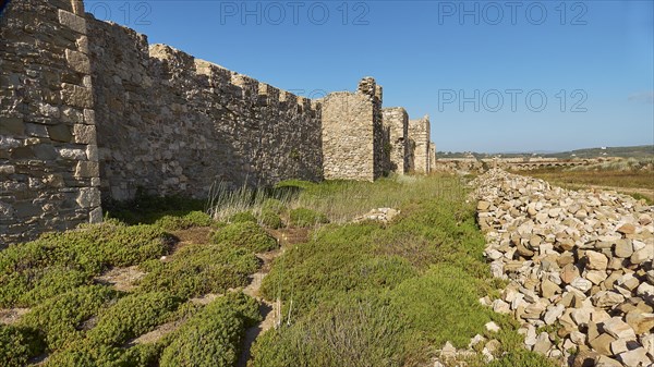 Historical ruins of an ancient wall under a clear blue sky with surrounding vegetation, sea fortress Methoni, Peloponnese, Greece, Europe
