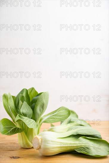 Fresh green bok choy or pac choi chinese cabbage on a brown wooden background. Side view, copy space, selective focus