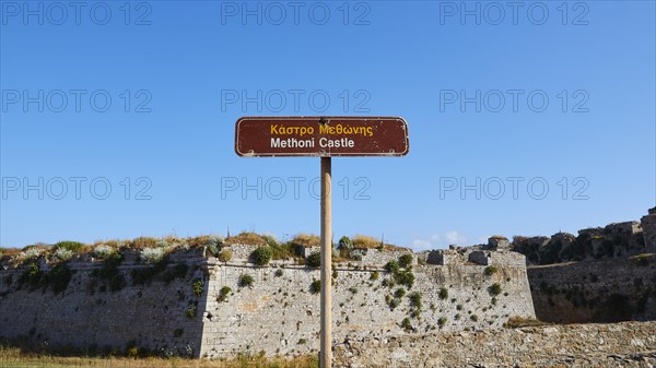 Brown signpost against a blue sky points towards Methoni Castle, Methoni sea fortress, Peloponnese, Greece, Europe