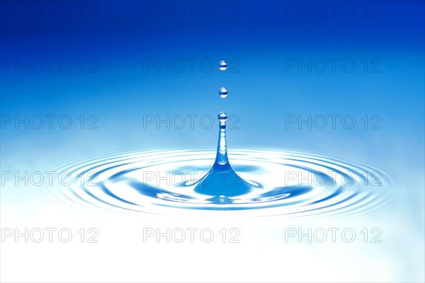 A drop of water jumps upwards from the water surface
