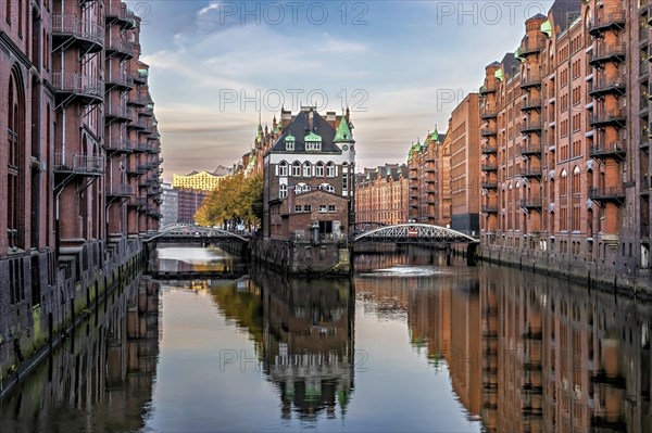 The Elbschloesschen in the morning light in the warehouse district of Hamburg with a great reflection in the canal and illuminated facades