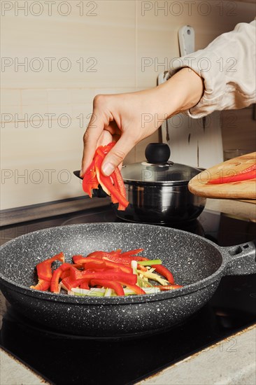 Dropping sliced bell pepper into frying pan