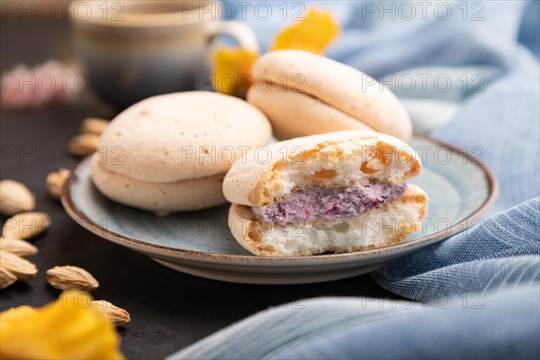 Meringues cakes with cup of coffee on a black concrete background and blue linen textile. Side view, close up, selective focus