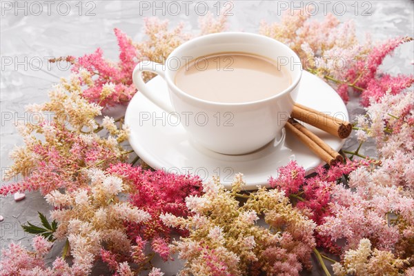 Pink and red astilbe flowers and a cup of coffee on a gray concrete background. Morninig, spring, fashion composition. side view, close up
