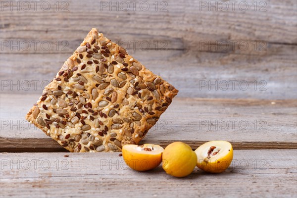 Biscuits with flax, sesame and sunflower seeds and yellow quince fruit on a rustic wooden background
