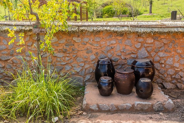 Ceramic fermentation jars sitting in front of mud and stone wall in urban public park in South Korea