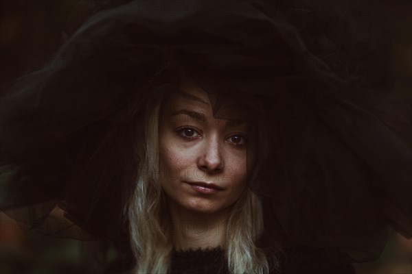 An intense portrait of a woman with a large black hat and a piercing gaze