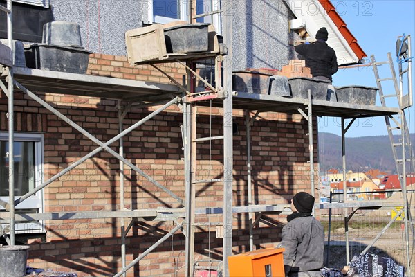 Bricklaying, clinker brick work. Bricklayers clad the facade of a detached house with clinker bricks
