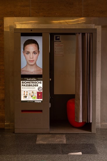 A photo booth for biometric passport photos with a female face on the advertising poster, Magdeburg, Saxony-Anhalt, Germany, Europe