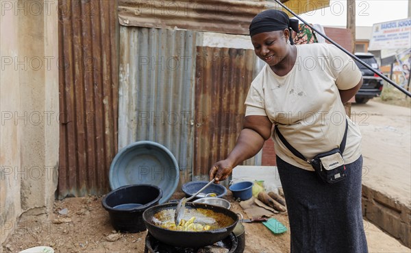 Young African woman frying potatoes for sale on the street, Nyanya, 06/02/2024