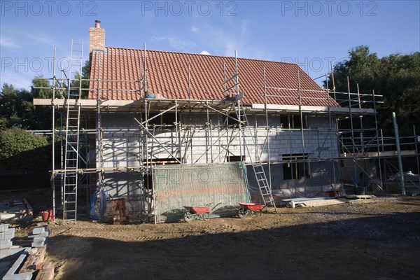 Detached house with scaffolding on new building construction, Shottisham, Suffolk, UK