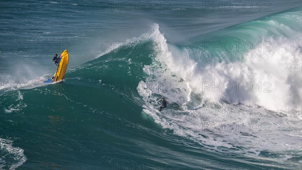 A jet ski and a surfer on a rolling wave, Nazare, Portugal, Europe