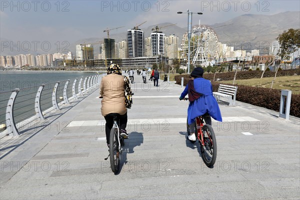 Two woman ride their mountain bikes at Lake Chitgar in Tehran, Iran. Lake Chitgar is an artificial lake in the north-west of Tehran, also known as the Lake of the Martyrs of the Persian Gulf, 10.03.2019
