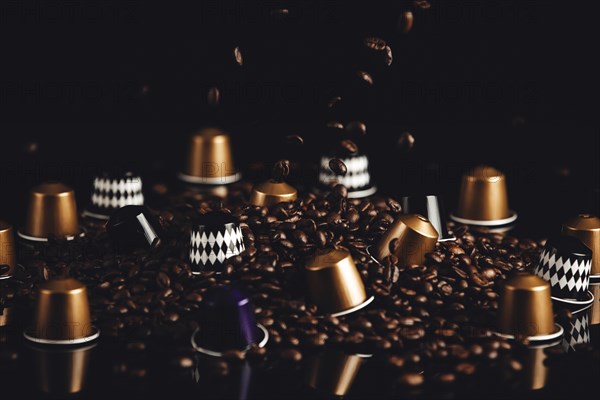 Scattered coffee capsules and coffee beans with falling coffee beans on a dark background