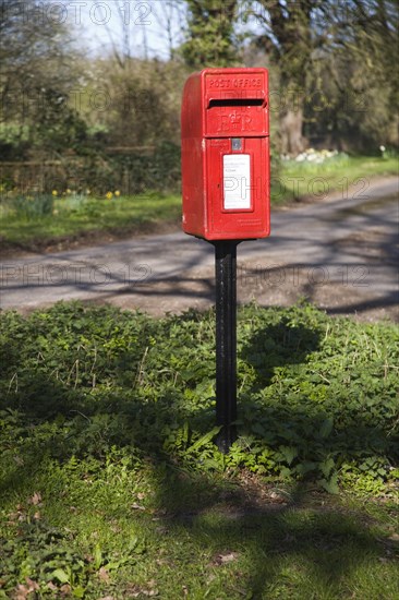 Red rural post box on its own at small road junction, Boulge, Suffolk, England, United Kingdom, Europe