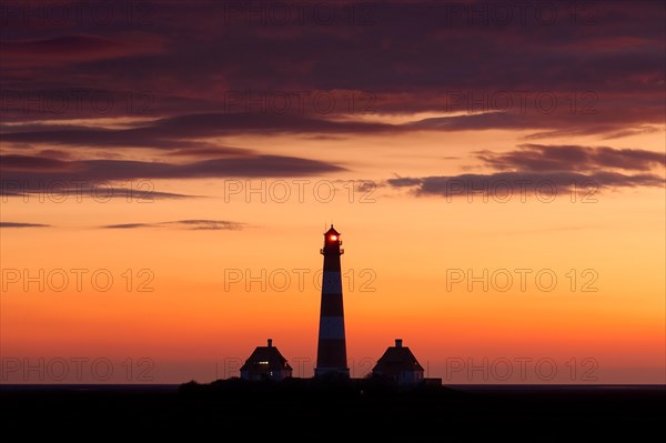 Lighthouse Westerheversand silhouetted against orange sunset sky, Westerhever, Wadden Sea National Park, North Frisia, Schleswig-Holstein, Germany, Europe