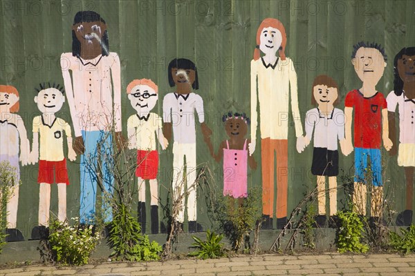 Mural painted on wooden fence of children of different ages holding hands, UK