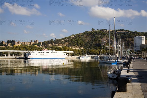 Alcantara Dos catamaran ferry at the quayside in new port development in Malaga, Spain with the historic Alcazaba fortress behind