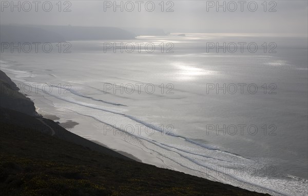 Seascape clouds sunlight waves breaking on a sandy beach off St Agnes Head, north Cornwall, England, United Kingdom, Europe