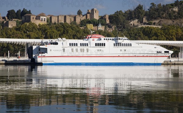 Alcantara Dos catamaran ferry at the quayside in new port development in Malaga, Spain with the historic Alcazaba fortress behind