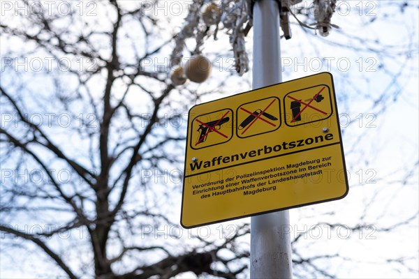 Yellow sign on a post with the inscription 'Weapons Prohibition Zone' and two crossed firearms, Magdeburg, Saxony-Anhalt, Germany, Europe
