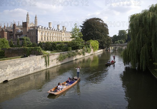 People punting in small boats on the River Cam, Cambridge England with Clare College in the background