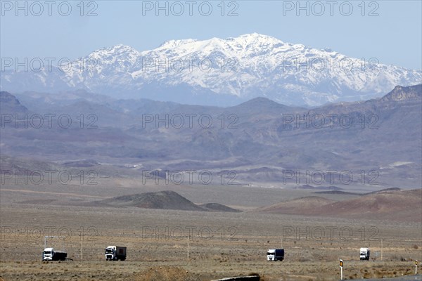 Truck on a motorway in the central desert of Iran, snow-capped mountains can be seen in the background, 13.03.2019