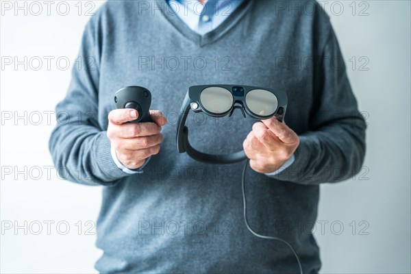 Studio photo with close-up of the hands of a man holding a remote control and intelligent mixed reality goggles