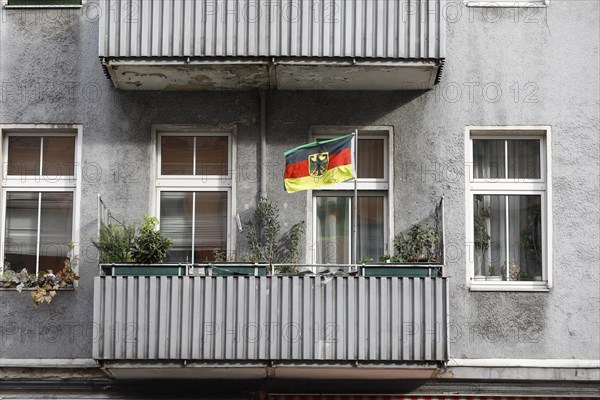 A German flag with a federal eagle flutters on the balcony of a run-down apartment building, Berlin, 11 October 2019