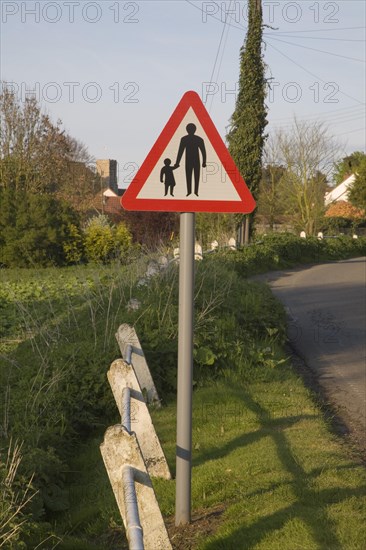 Red triangular Highway Code child and adult road sign warning of no pavement ahead, Suffolk, UK