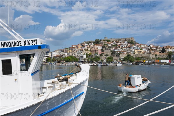 A boat in the foreground with a view of a hillside town by the sea under a partly cloudy sky, Old Town, Kavala, Dimos Kavalas, Eastern Macedonia and Thrace, Gulf of Thasos, Gulf of Kavala, Thracian Sea, Greece, Europe