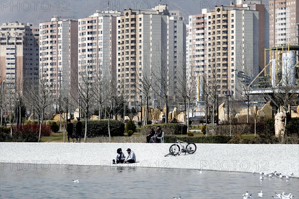 A young couple sits on the beach of Lake Chitgar in Tehran, Iran. Lake Chitgar is a man-made lake in the north-west of Tehran, also known as the Lake of the Martyrs of the Persian Gulf, 10 March 2019