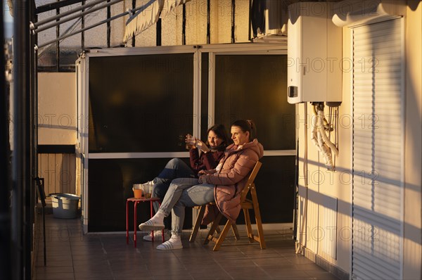 Two young woman enjoying sunset, evening light on terrace, drink, coat, Thessaloniki, Macedonia, Greece, Europe