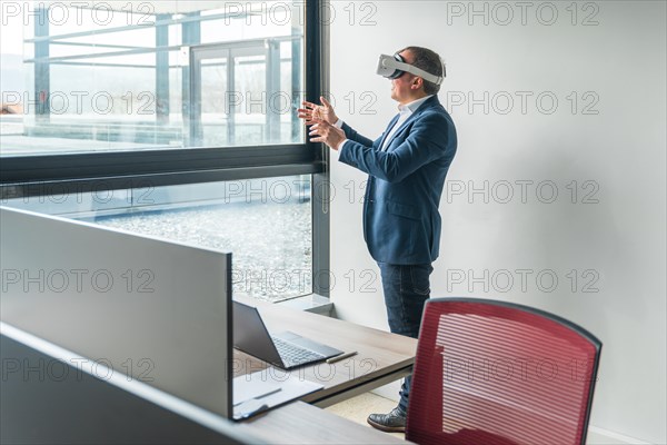 Businessman standing wearing 3D glasses at work in the office facing the windows