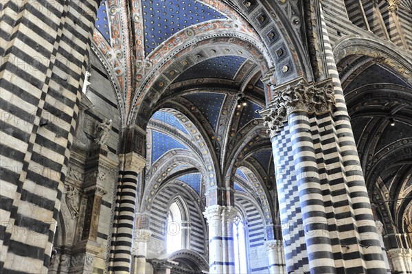 The nave of the cathedral with its black and white striped marble columns, cross and round arches, Siena, Tuscany, Italy, Europe