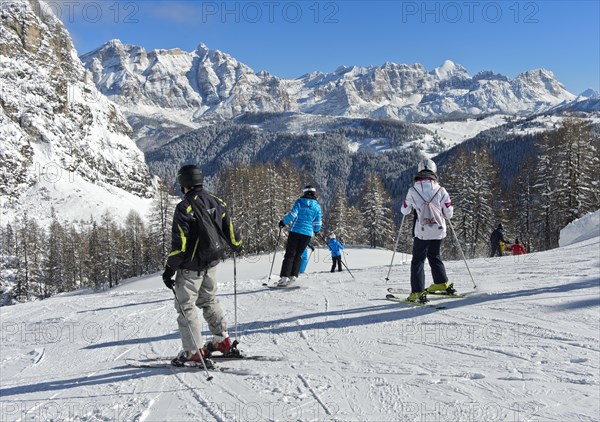 Skiers on a piste in front of the snow-covered mountain range of the Dolomites, winter sports resort Colfosco, Colfosco, Alta Badia ski area, Dolomites, South Tyrol, Italy, Europe